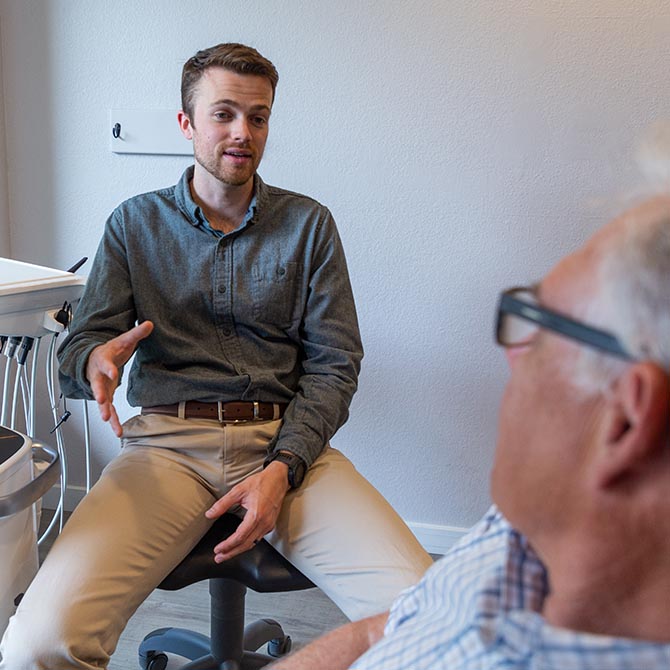 Dr. Tanner Menard talks to a male elder patient inside his clinic