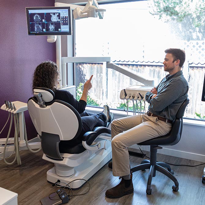 Dr. Tanner Menard listens to a female patient sitting at the dental chair inside the Palouse View Dental office