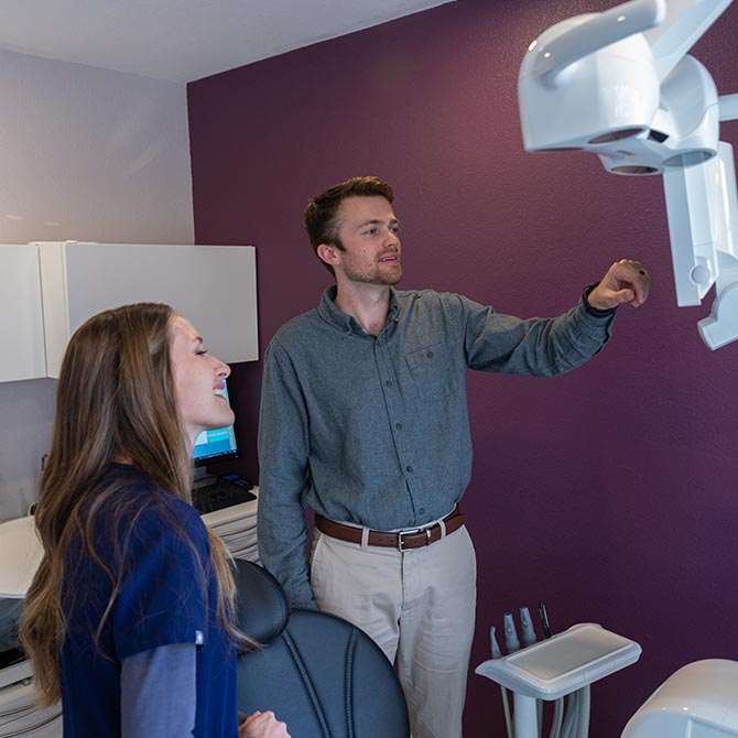 Dr. Tanner Menard works on the computer monitor with a female dental staff member.